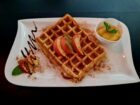 Frisch gebackene Waffel mit Zimt und Apfelscheiben, serviert mit Apfelmus – Der ideale süße Genuss.