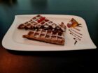 Schokoladen-Waffel mit Puderzucker und frischen Früchten – ein himmlischer Genuss bei Mokka & Minze.