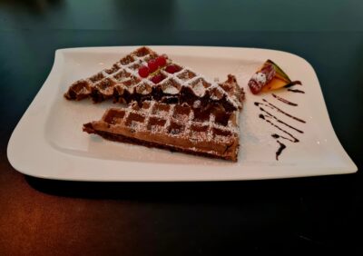 Schokoladen-Waffel mit Puderzucker und frischen Früchten – ein himmlischer Genuss bei Mokka & Minze.